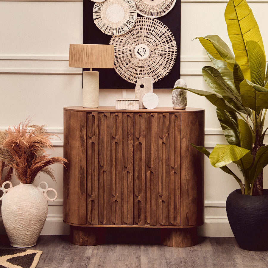 Wooden side table with decorative items against a wall with abstract art