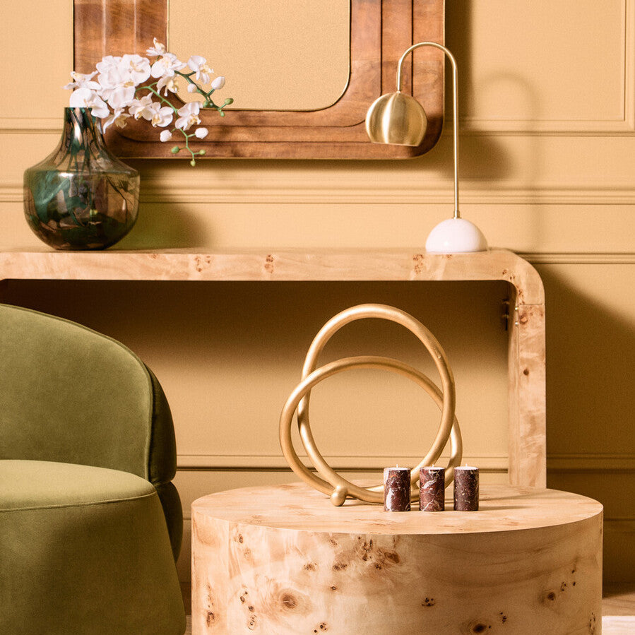 Wooden box with handles on a wooden surface, green chair and decorative items in the background.