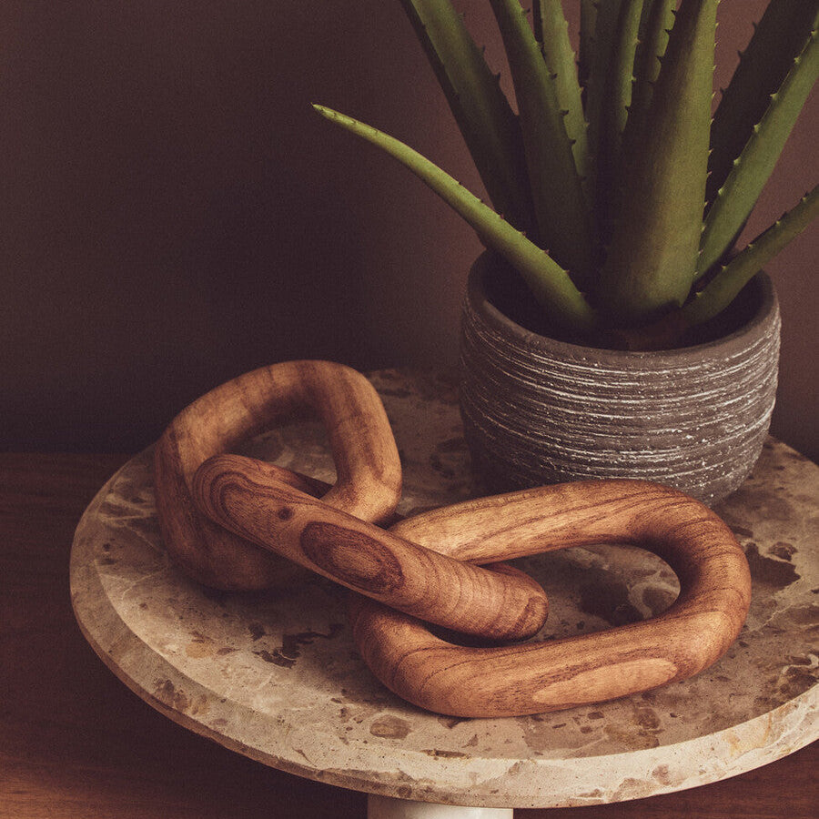 Wooden chain on a stone surface with a potted plant in the background