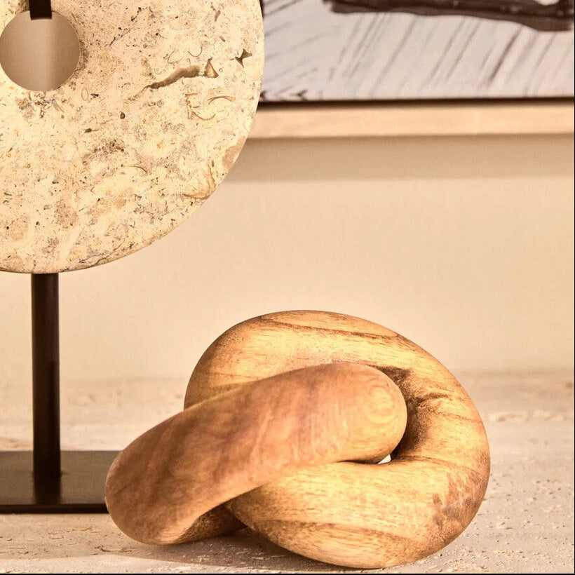 Decorative stone lamp and wooden knot sculpture on a surface with a blurred abstract painting in the background.