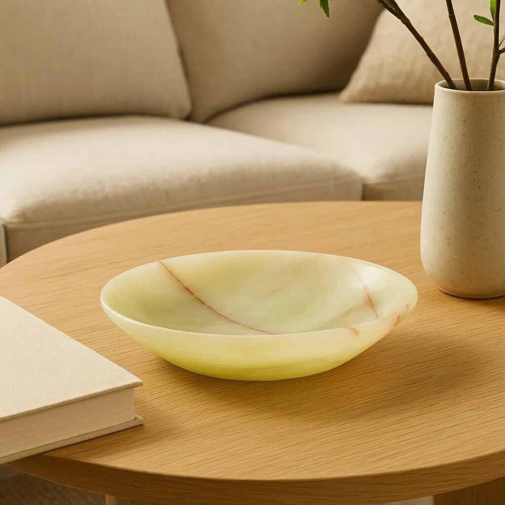 Round wooden coffee table with a decorative bowl, book, and vase in a living room setting.