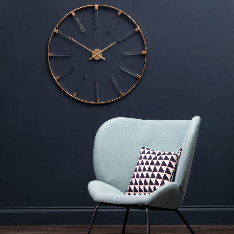 Modern chair with a geometric pillow against a dark blue wall with a decorative clock.