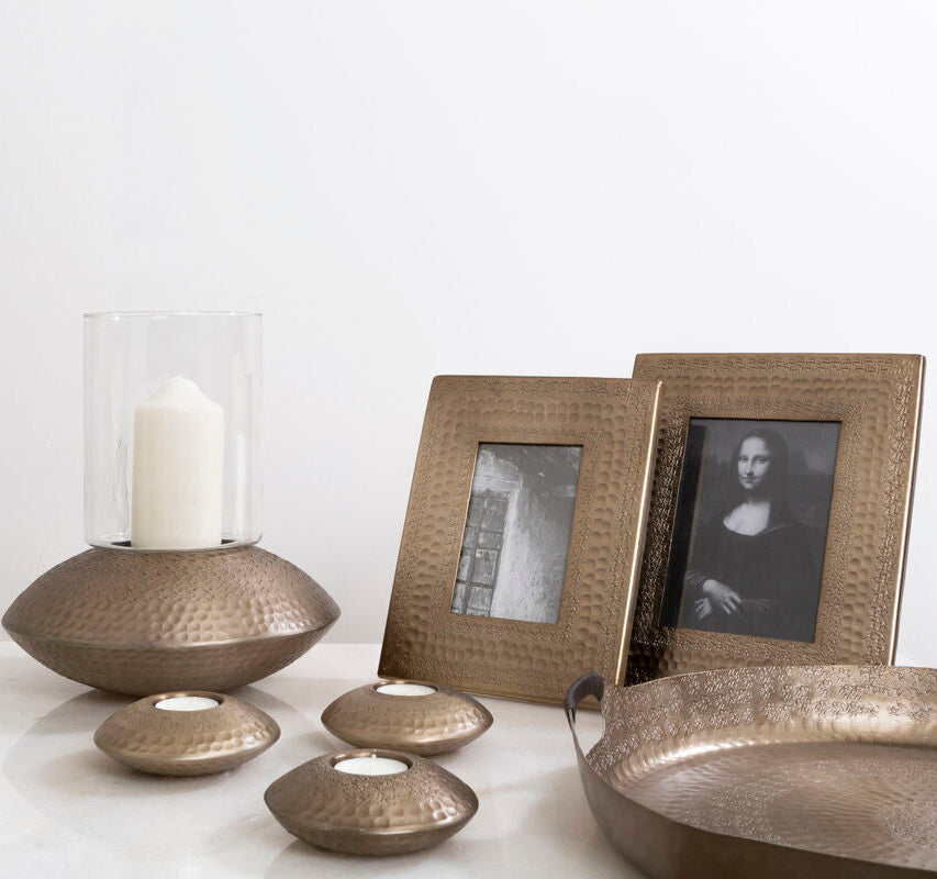 Decorative items including a candle holder, picture frames, and a tray on a white surface.