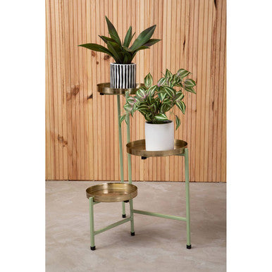 Three-tiered metal plant stand with potted plants against a wooden wall.