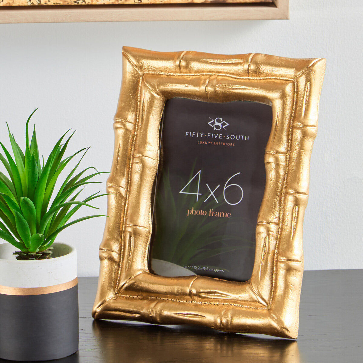 Gold photo frame with a plant on a gray surface