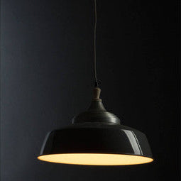Black pendant light with a warm glow against a dark background