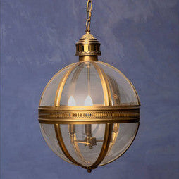 Decorative pendant light with gold frame and clear glass sphere on a blue background