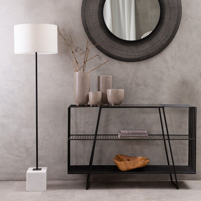 Modern interior with round mirror, console table, and floor lamp against a gray wall.