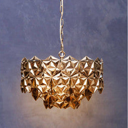 Gold geometric pendant light against a textured purple background