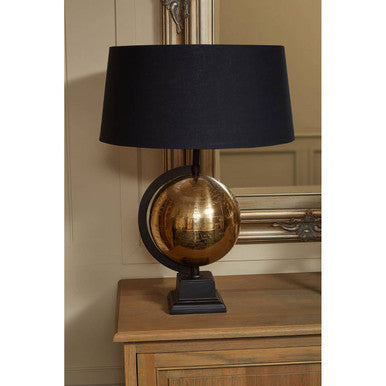 Table lamp with black shade and gold base on a wooden surface.