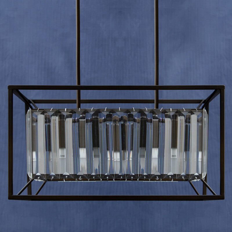 Modern pendant light with rectangular glass shade against a blue background