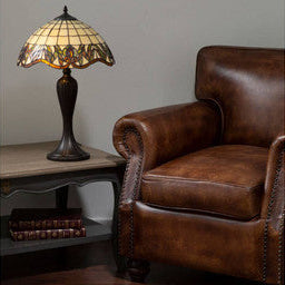 Brown leather armchair next to a table lamp with a decorative shade in a room.