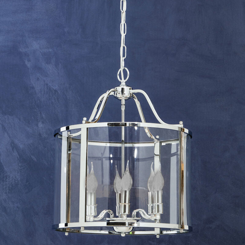 Pendant light fixture with clear glass shade against a blue background
