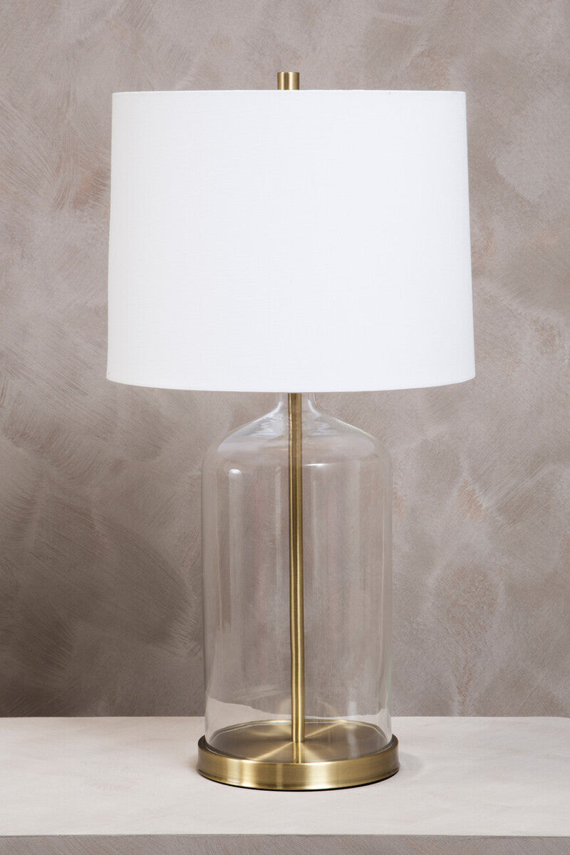 Table lamp with white shade, gold base, and clear glass cover on a neutral background