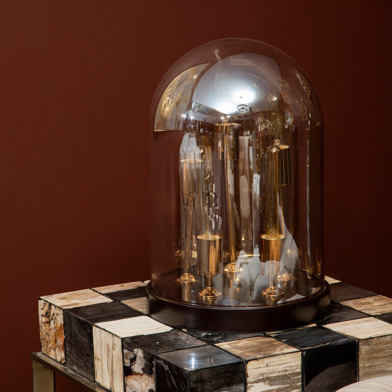 Decorative object under a glass dome on a checkered surface with a dark background