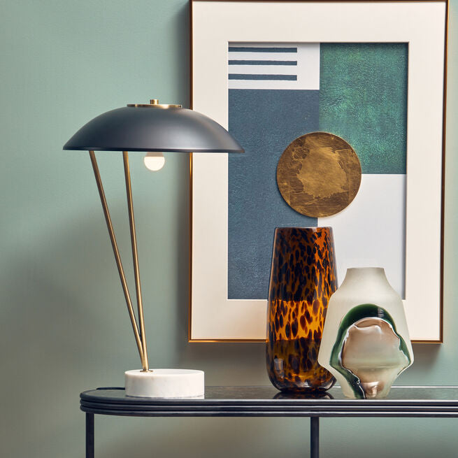Console table with decorative items against a wall with a framed abstract painting.