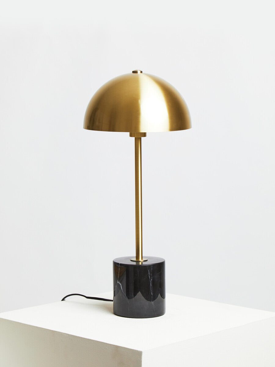 Gold table lamp with black base on a white surface