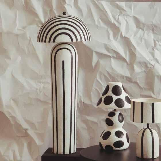Decorative vases and a lamp with black and white patterns on a textured white background