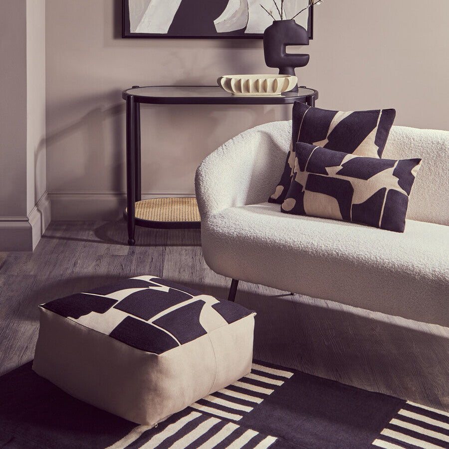 Modern living room with a sofa, ottoman, and abstract art on the wall.