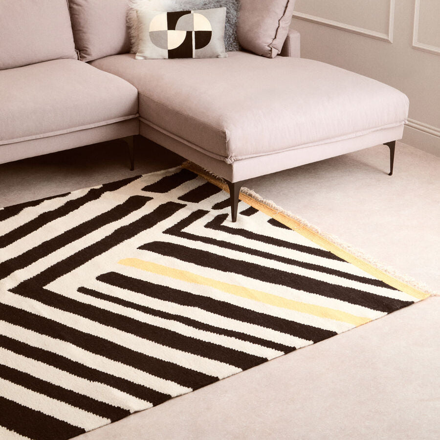 Modern living room with a gray sectional sofa and a geometric patterned rug.