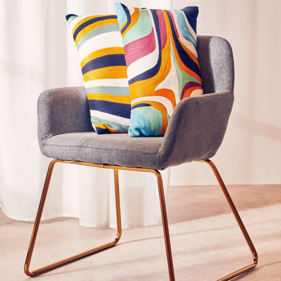 Gray chair with colorful striped cushions on a light wooden floor.