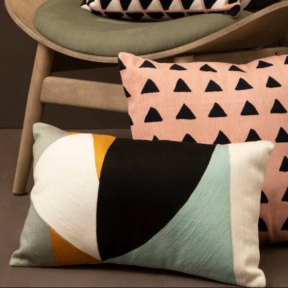 Colorful geometric-patterned cushions on a chair against a dark background