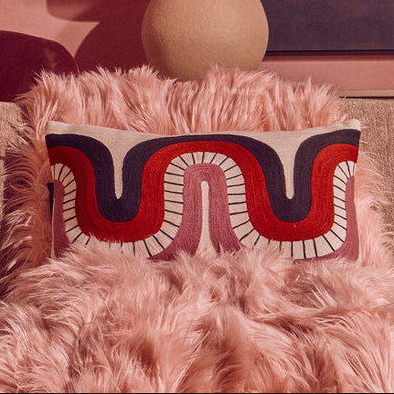 Fluffy pink pillow with decorative patterns on a textured surface