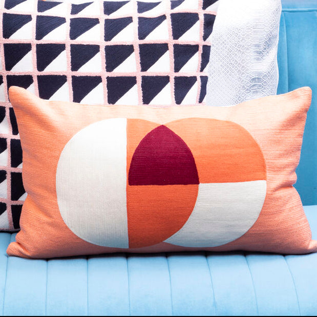 Two decorative pillows on a blue couch with a colorful abstract pattern in the background.