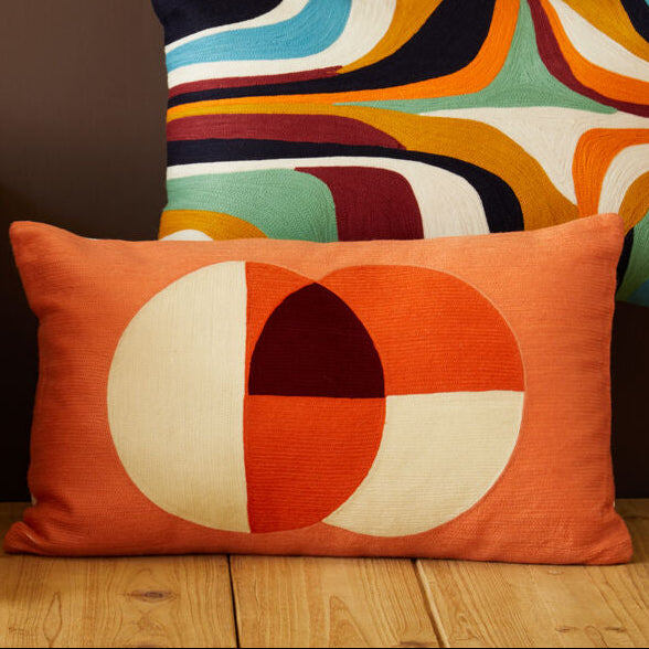 Colorful patterned pillows on a wooden floor against a brown wall