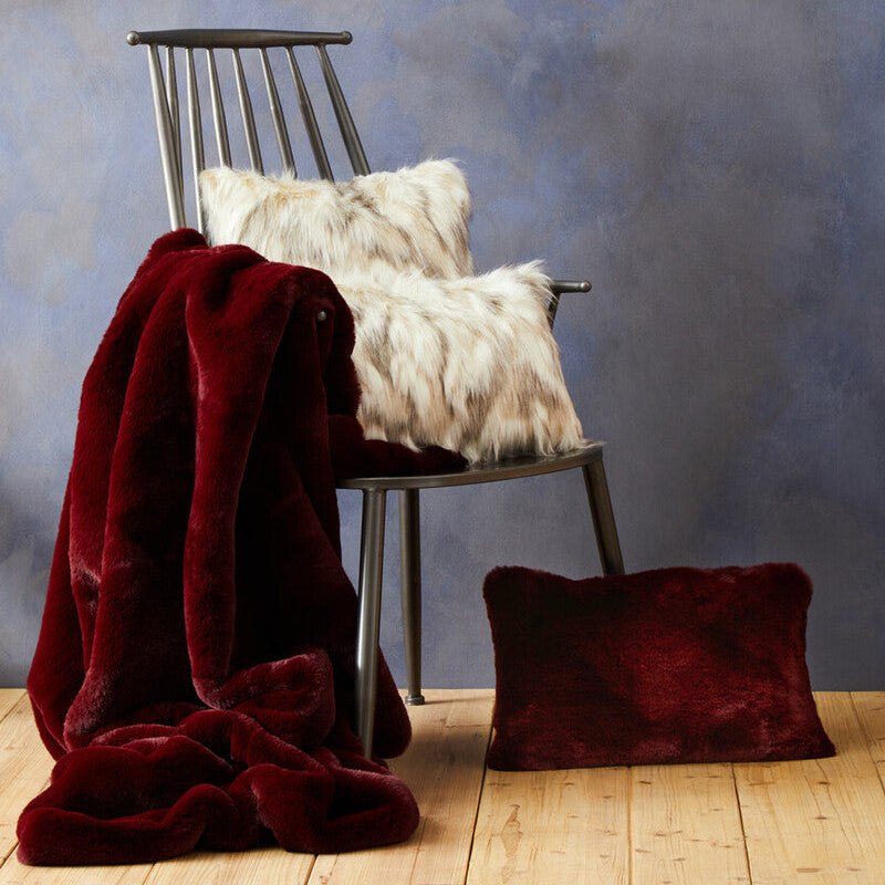 Chair with a red blanket and white pillows against a textured blue wall.