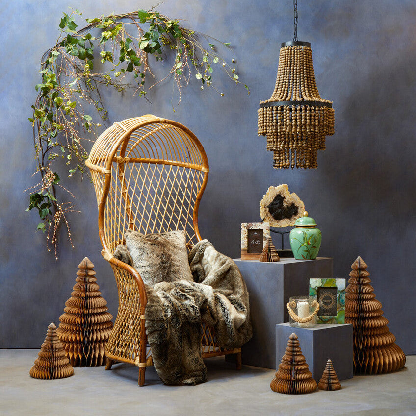 Decorative room with wicker chair, hanging lamp, and decorative trees against a textured wall.