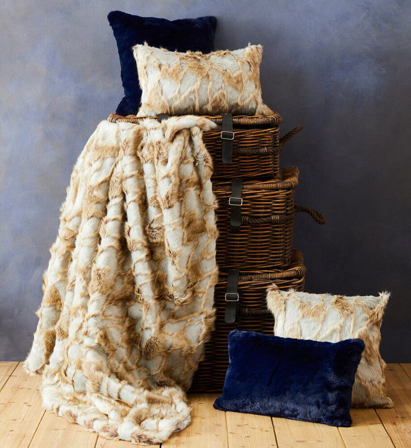 Textured throw blanket and pillows on a wooden surface with a gray background
