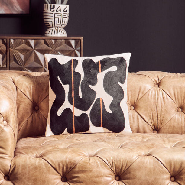 Brown tufted sofa with a decorative pillow in a living room setting.