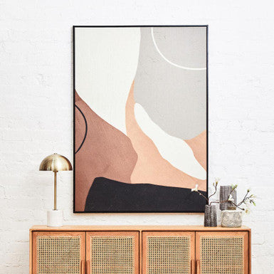 Abstract art piece on a wall above a wooden cabinet with decorative items.