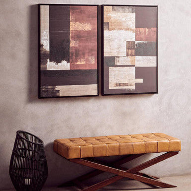 Two abstract wall art pieces above a brown leather bench against a gray wall.