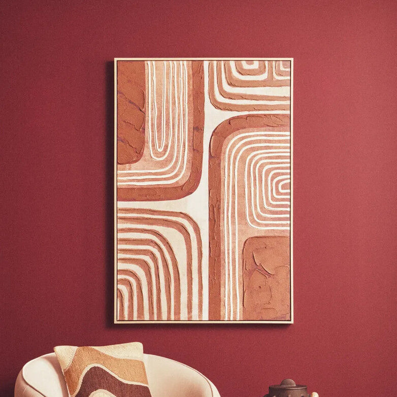 Modern armchair with a decorative pillow in a room with a red wall and abstract art.