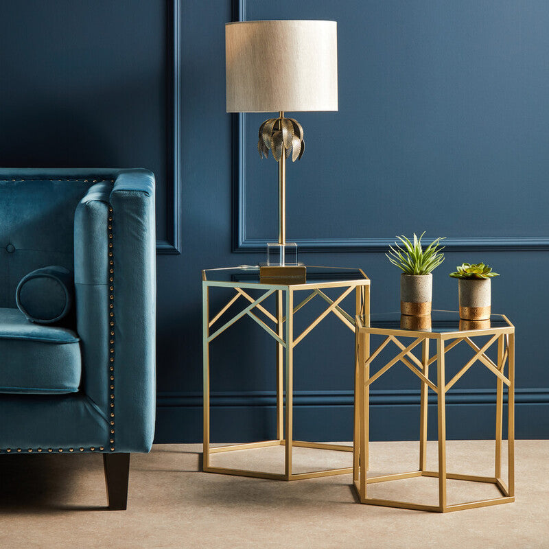 Gold side table with lamp and plants against a blue wall