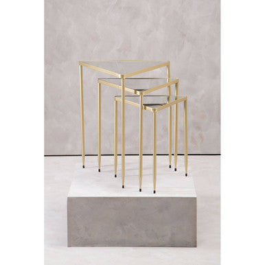 Set of three gold nesting tables on a gray platform with a neutral background