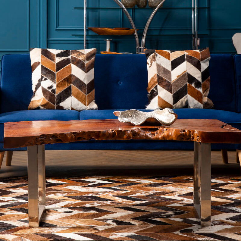 Blue sofa with patterned cushions and a wooden coffee table in a room with blue walls.