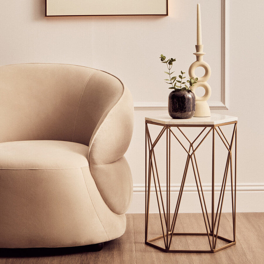 Beige armchair in a living room with a side table and decorative items.