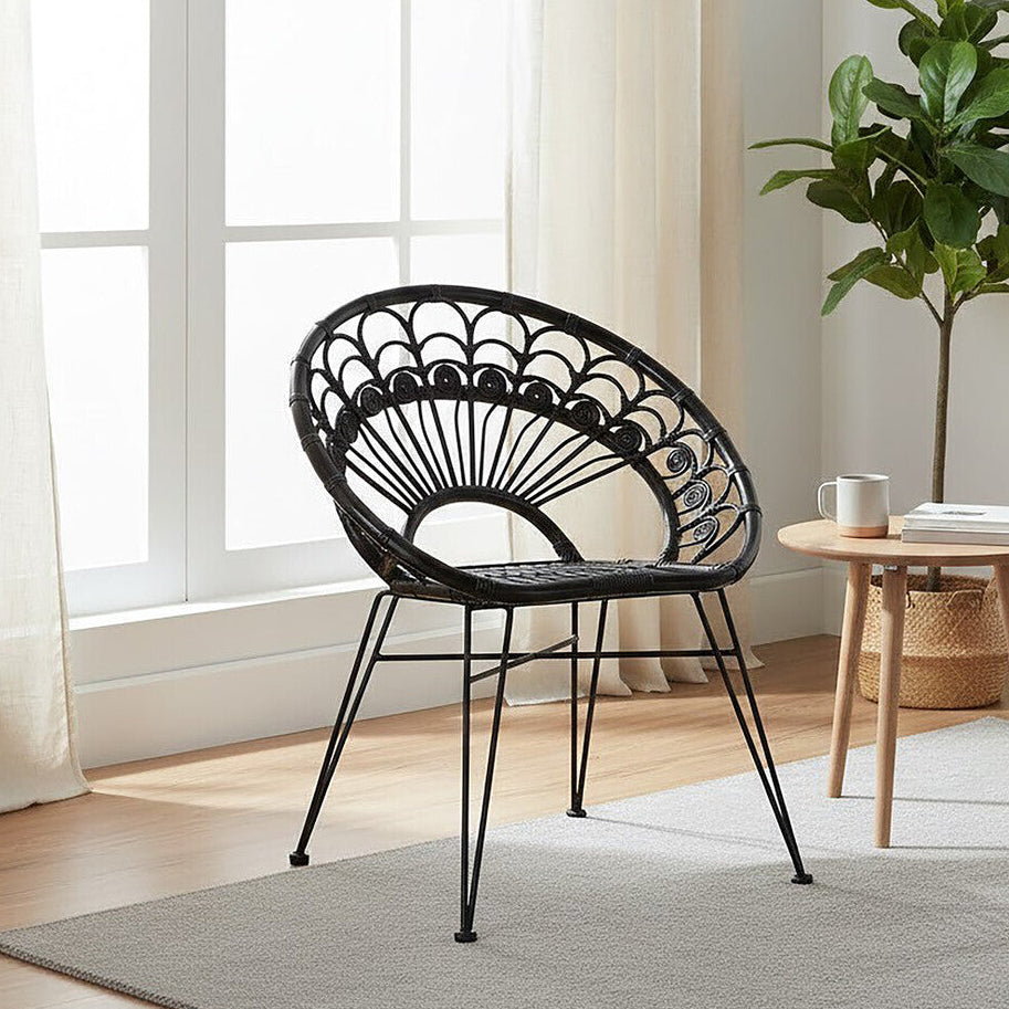 Black decorative chair in a bright room with a plant and small table.