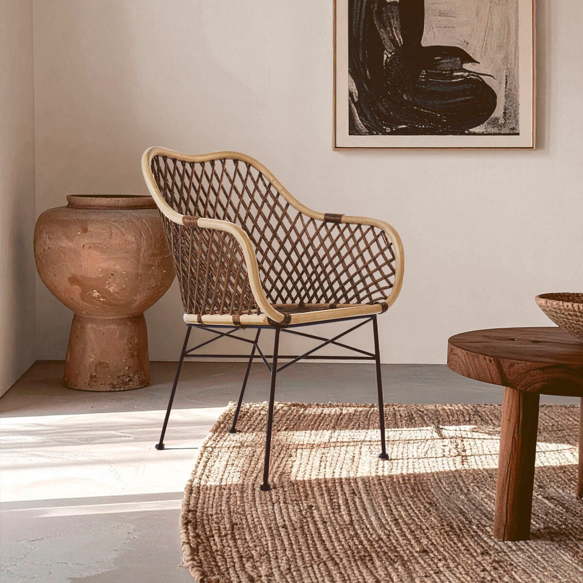 Woven chair in a room with a textured rug, wooden table, and decorative vase.