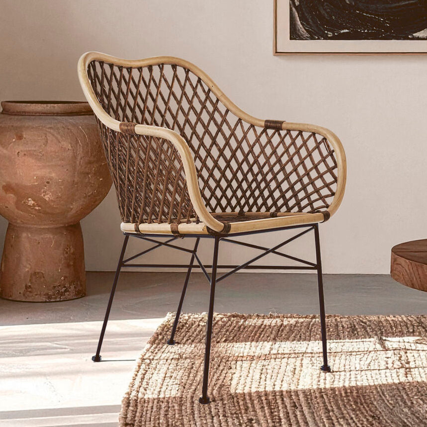 Woven chair in a room with a textured rug, wooden table, and decorative vase.