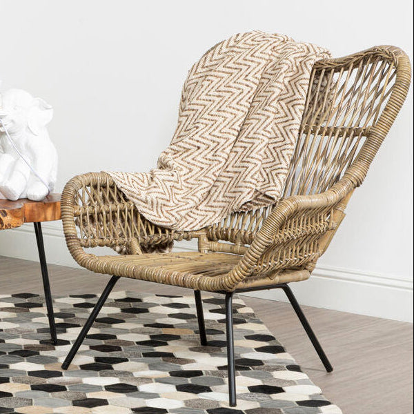 Wicker chair with a patterned cover in a room with a wooden table and decorative items.