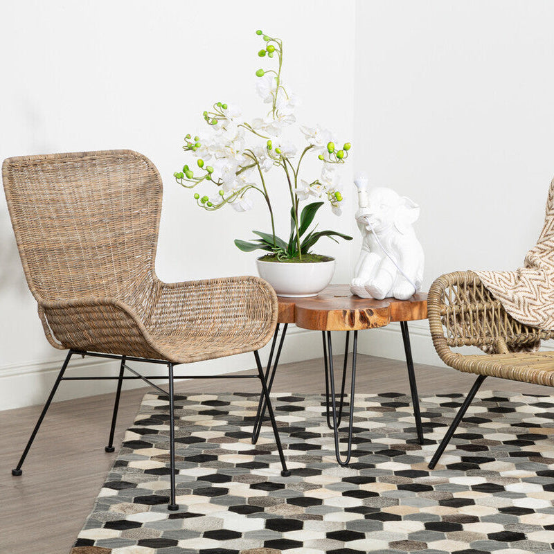 Two wicker chairs with a small round table and decorative items on a geometric patterned rug.