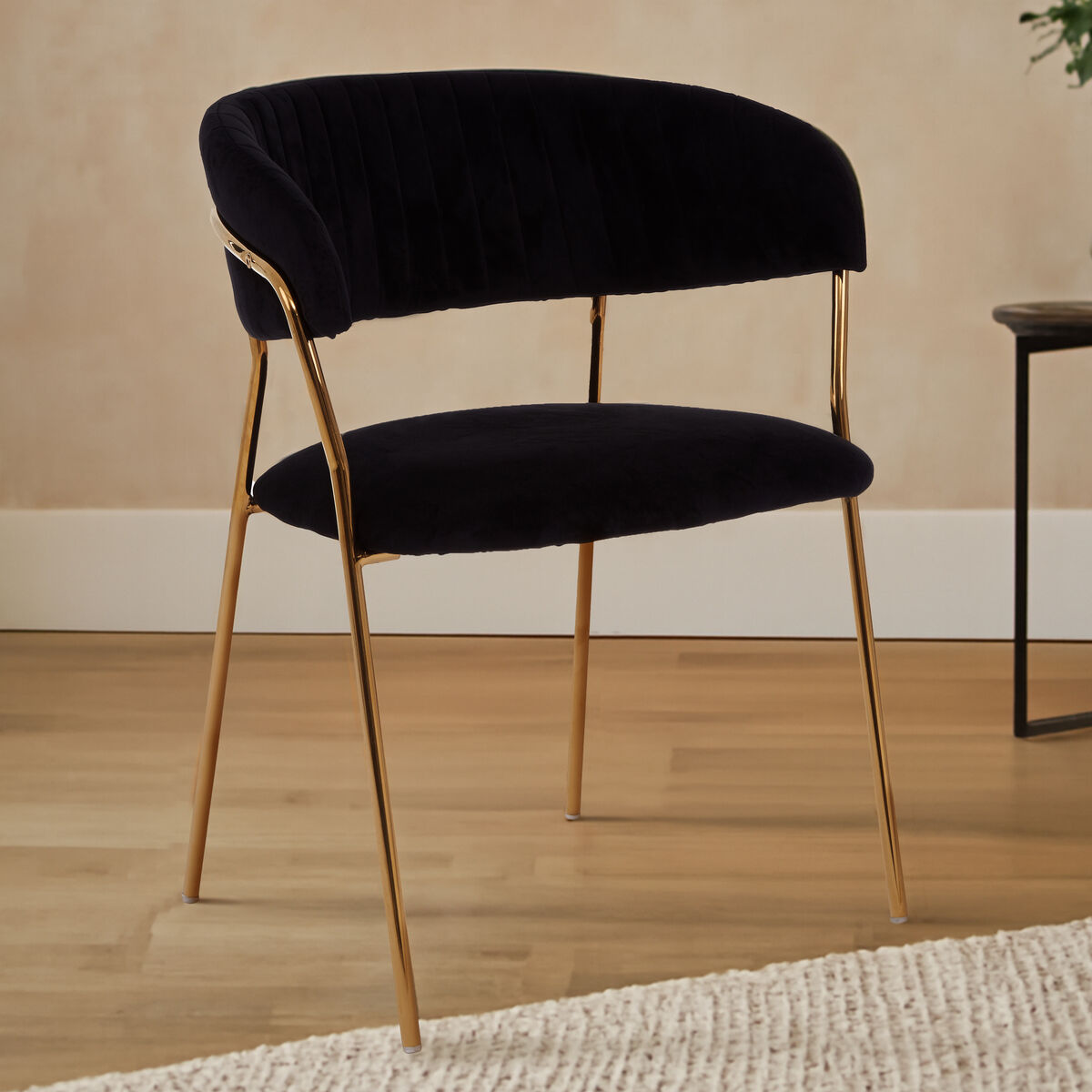 Black upholstered chair with gold legs on a wooden floor.