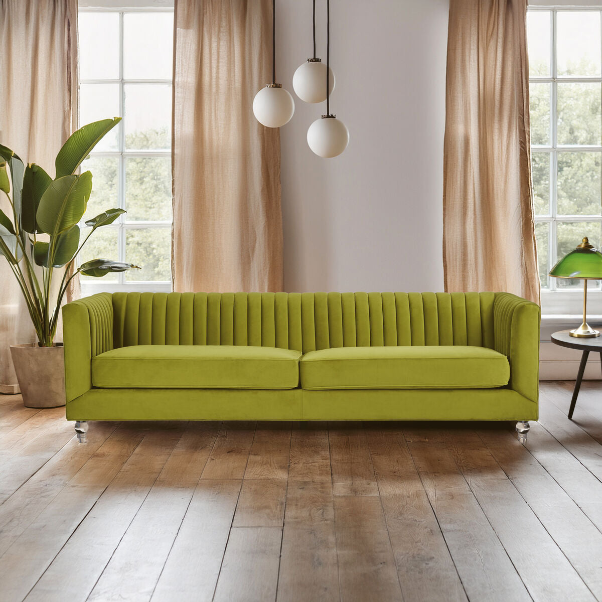 Green sofa in a modern living room with large windows and decorative plants.