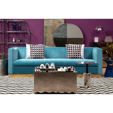 Modern living room with a blue sofa, coffee table, and decorative pillows against a purple wall.