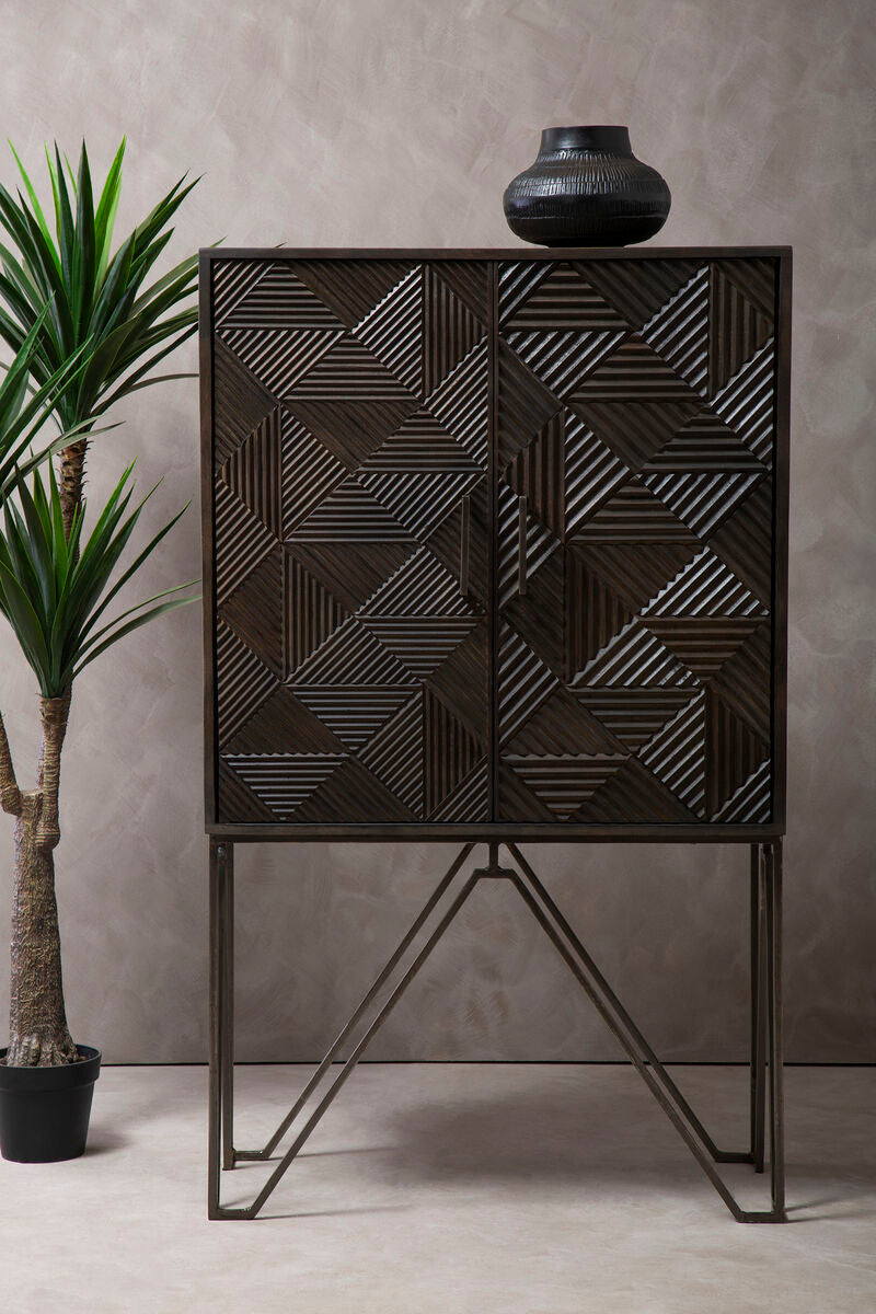 Black geometric-patterned cabinet with a vase on top against a gray wall.