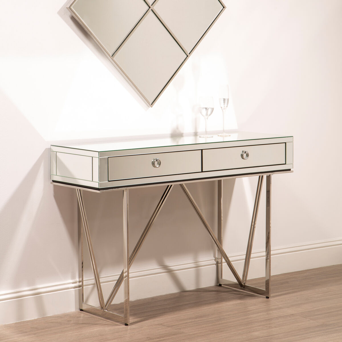 Decorative console table with mirrored surface and metal legs against a wall.